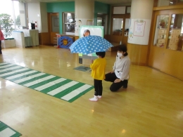 幼児が傘をさして、横断歩道を渡る様子